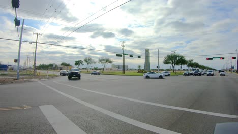 POV-while-waiting-at-a-traffic-light-on-a-busy-four-lane-street-with-green-space-visible