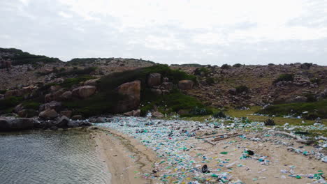 Aerial-circular-view-of-polluted-beach-in-Ninh-Thuan,-full-of-colorful-plastic-bags