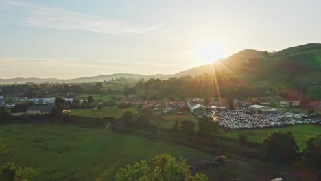 Scenic-aerial-view-of-little-hamlet-in-green-valley-under-idyllic-sunset