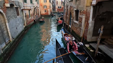 Gondolas-and-gondolier-rowing-in-city-canal,-Venice-in-Italy