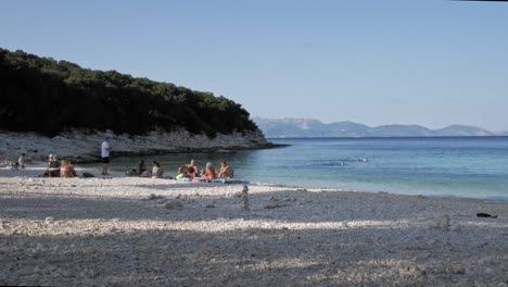 Touristen-Entspannen-Sich-Im-Sommer-Am-Ufer-Des-Strandes-Von-Paralia-Emplisi-In-Griechenland-–-Weitwinkelaufnahme