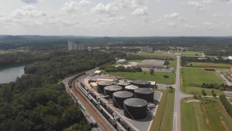 train-yard-shipping-industry-logistics-oil-gasoline-crude-silo-forest-lake-environment-aerial-drone-tilt-reveal-georgia-united-states-america