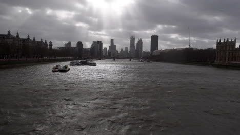 Los-Rayos-Del-Sol-Y-Las-Nubes-Oscuras-Se-Mueven-Rápidamente-Sobre-Un-Río-Támesis-Muy-Agitado-Y-Rascacielos-Distantes-Y-Grúas-De-Construcción-Durante-La-Tormenta-Eunice