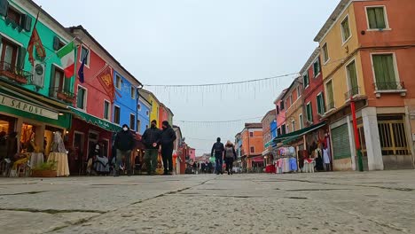 Low-angle-ground-surface-first-person-pov-of-people-walking-in-Burano-downtown-and-colored-houses