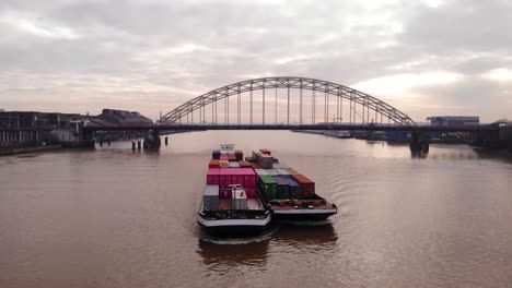 Luftaufnahme-Eines-Excelsior-Frachtschiffs-Und-Eines-Lastkahns,-Die-Frachtcontainer-Auf-Dem-Fluss-Noord-Transportieren,-Mit-Brug-Over-De-Noord-Im-Hintergrund