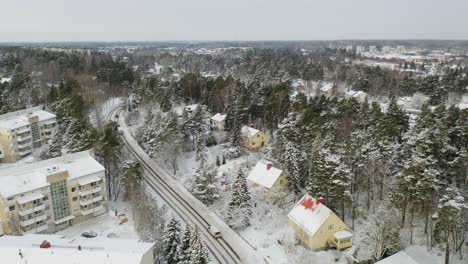 Aerial-fly-over-following-twisting-road-above-Turku-suburbs-after-snowfall-when-everything-is-covered-in-snow