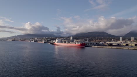 Drone-flying-towards-cargo-ship-in-Vancouver-commercial-port,-Canada