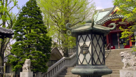 Asakusa,-Tokio,-Japón-Alrededor-De-Abril-De-2020:-Una-Mujer-Adorando-En-Un-Auténtico-Templo-Japonés,-Con-Líneas-De-árboles-Y-Escaleras,-Linternas-Tradicionales-En-Un-Tranquilo-Y-Tranquilo-Jardín-De-Estilo-Zen-En-Un-Día-Soleado