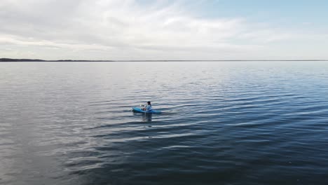 The-magnificent-clear-blue-water-of-buffalo-lake,-Alberta-with-a-woman-rowing-in-a-kayak