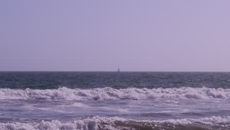 Panning-shot-of-a-lone-sailboat-in-the-ocean-on-a-bright-sunny-day-panning-from-right-to-left