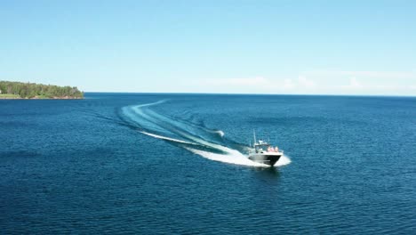 Aerial,-luxury-speedboat-sailing-fast-on-vast-blue-ocean-next-to-island