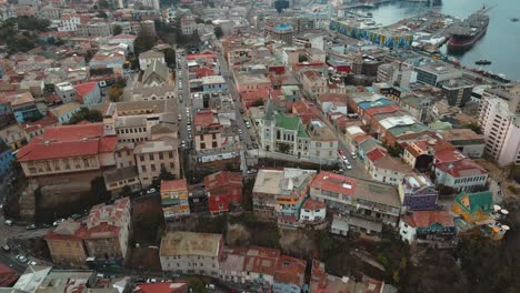 Aerial-orbit-of-colorful-houses-and-Lutheran-Church-in-Cerro-Concepcion,-Valparaiso-city-and-Sea-Port-in-back,-Chile