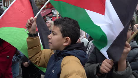 Two-young-boys-join-in-chants-and-wave-flags-on-a-pro-Palestinian-protest-outside-the-London-Israeli-embassy-in-slow-motion