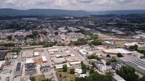Aerial-hyperlapse-of-Main-Street-in-Chattanooga,-Tennessee-slowly-zooming-in-on-train-tracks-and-moving-trains