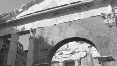 Black-and-white-tilt-up-shot-of-entrance-of-colonnaded-Portico-of-Octavia-in-the-Roman-Ghetto-next-to-Teatro-di-Marcello-in-Rome,-Italy-at-daytime