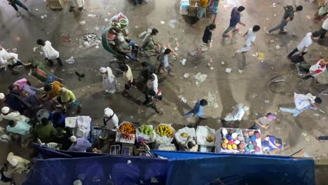 Vista-Panorámica-De-La-Vida-Nocturna-A-Lo-Largo-De-La-Calle-Con-Lugareños-Y-Conductores-De-Rickshaw-Pasando-Por-El-Puesto-De-Comida