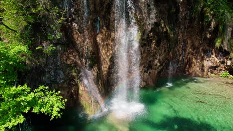 Dramatic-drone-clip-starting-out-on-waterfall,-then-ascending-to-top-down-orbit,-ending-on-tilt-up-reveal-of-gorgeous-Plitvice-Lakes