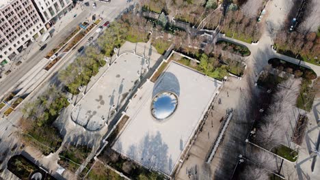 Aerial-view-away-from-the-cloud-gate,-revealing-skyscrapers-in-Chicago,-USA---tilt,-drone-shot