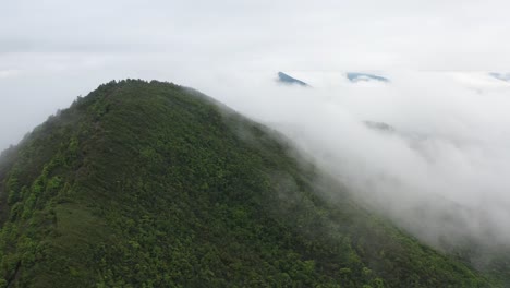Luftaufnahme-Grüner-Berge-Voller-Vegetation,-Eingehüllt-In-Weiße-Wolken