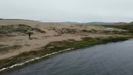 Overtake-Shot-Of-People-Walking-On-Blue-Sea-Bank-Surrounded-By-Water,-California