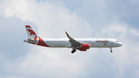 Canada-Rouge-airplane-flying-through-a-partially-cloudy-sky