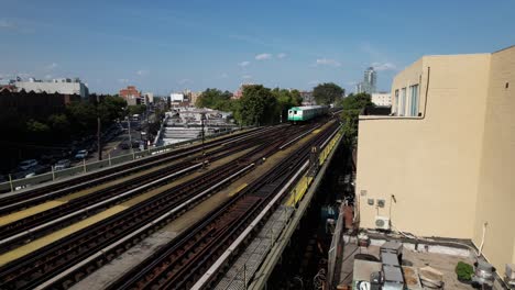 An-aerial-view-of-elevated-tracks-with-historic-NYC-subway-trains-travelling-towards-the-camera-on-a-sunny-day