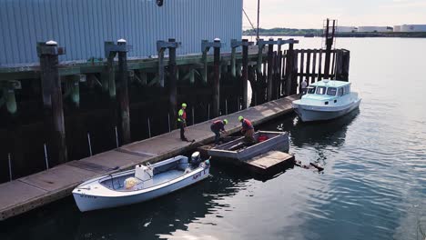 Men-attempting-to-lift-a-large-piece-of-metal-salvage-onto-boat