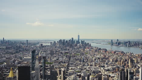 Wide-panoramic-view-of-Manhattan-with-the-One-World-Trade-Center-and-the-Statue-of-Liberty-in-the-distance-on-a-sunny-day,-static-shot