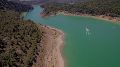 Aerial-drone-view-of-motorboat-traveling-through-turquoise-water-river