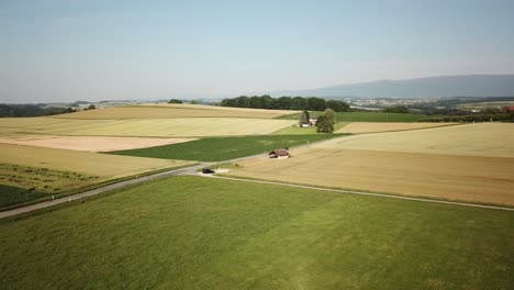Campiña-Suiza-Con-Diferentes-Campos-Al-Lado-De-Una-Carretera-Capturada-Por-Drones,-Vaud