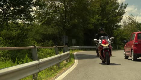 Man-riding-a-motorbike-to-a-beautiful-country-estate-in-Tuscany-in-bright-sunshine-on-a-long-road