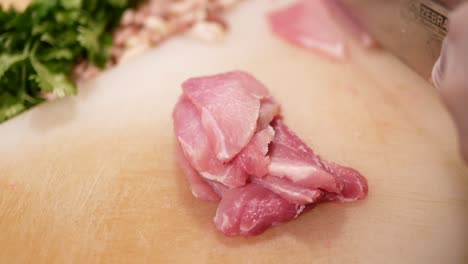 Hand-with-Glove-Use-Knife-to-Slice-Pork-Loin-into-Biting-Size-Pieces,-Close-Up