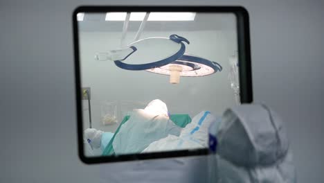 Asian-Woman-Wear-PPE-Look-Inside-Operating-Room-Window,-Close-Up