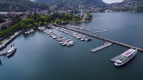 Yachts-and-Boats-in-Harbor-of-Beautiful-Lake-Como,-Italy---Aerial-TIlt-up
