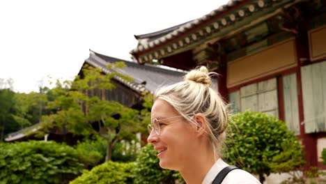 Slow-motion-shot-of-happy-woman-visiting-old-korean-Temple-in-South-Korea-during-sunny-day---close-up