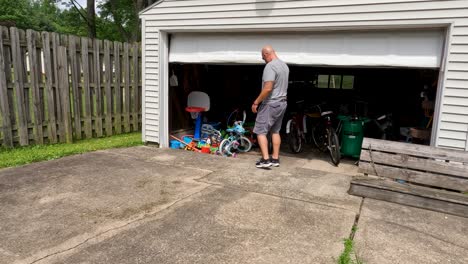 Adult-man-pulling-out-bicycle-stored-in-garage-for-exercise-in-sunny-day