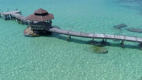 Drone-shot-of-wooden-footbridge-leading-into-the-sea