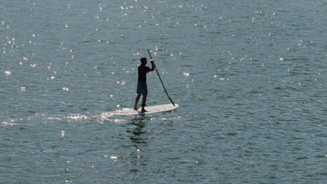 Silhouette-Eines-Stand-Up-Paddle-Boarders-Mit-Morgensonne,-Die-Sich-Auf-Dem-Wasser-Spiegelt