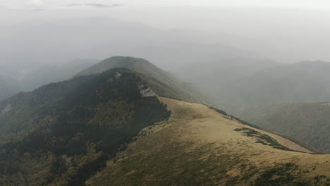 Ascending-aerial-shot-of-foggy-peak-covered-with-few-evergreens,-Slovakia