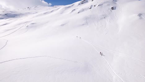Aerial-of-people-going-up-a-snowy-mountain-in-the-alps