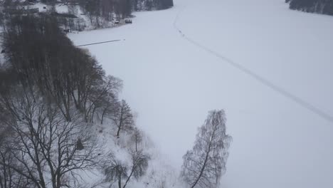 Aerial-tracking-shot-of-four-outdoor-enthusiast-going-for-daily-walk-on-big-deserted-frozen-lake
