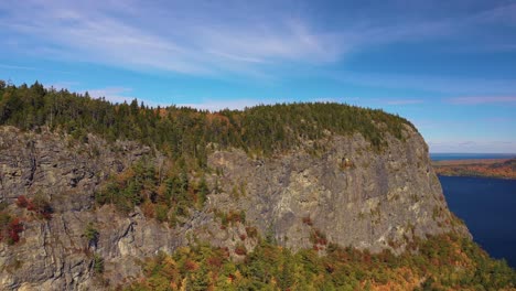 Aerial-footage-pushing-in-towards-cliff-face-on-Kineo-Mountain-in-peak-autumn-foliage