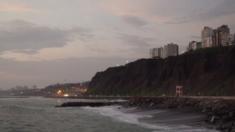 Sunset-over-sea,-highway-and-buildings-at-Malecón-de-Miraflores,-Lima,-Per?