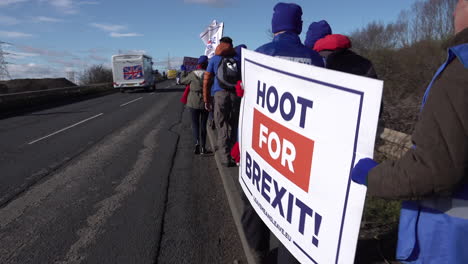 Two-men-hold-a-placard-“Hoot-for-Brexit”-as-people-walk-along-the-roadside-on-the-Leave-Means-Leave-camping-group-March-to-Leave-in-Hartlepool