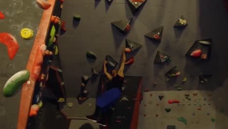 A-young-man-moves-from-one-support-to-another-hanging-on-a-wall-to-practice-climbing