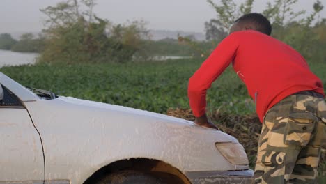 Nahaufnahme-Eines-Jungen-Afrikanischen-Mannes,-Der-Ein-Auto-Mit-Wasser-Aus-Dem-Victoriasee-Wäscht