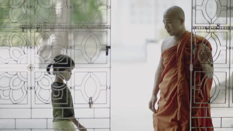 male-burmese-monk-with-traditional-clothes-opening-a-door-to-let-a-female-child-inside