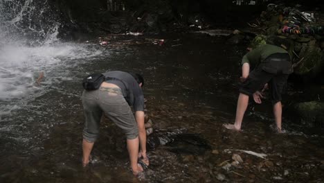 Slow-motion-shot-of-men-building-cairns-rock-sculpture-in-the-river-waters