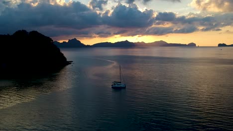 Luftaufnahme-Eines-Segelboots-Bei-Sonnenuntergang-Am-Las-Cabanas-Beach,-El-Nido,-Palawan,-Philippinen