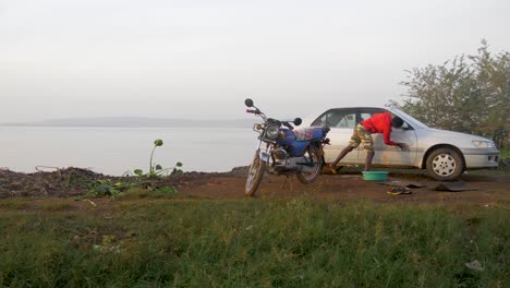Junger-Afrikanischer-Mann-Wäscht-Ein-Auto-Und-Ein-Motorrad-Am-Ufer-Des-Lake-Victoria